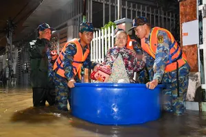 Cán bộ, chiến sĩ hỗ trợ người cao tuổi di dời ra khỏi vùng ngập sâu. Ảnh: LỮ ĐOÀN 681