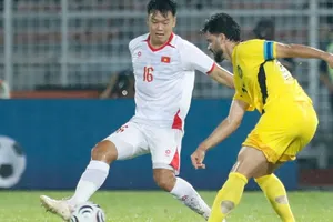 Trung vệ Thành Chung (trái) tranh chấp bóng với cầu thủ Malaysia ở trận bán kết lượt đi. ẢNH: ANH KHOA