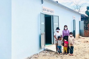 黃氏妙鸞老師與一名貧困學生在新房屋前合影。