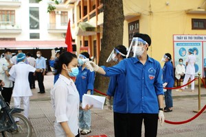 去年參加高中畢業考試的考生在量體溫。