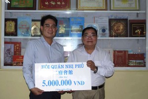 二府會館理事長彭偉強(右)把贈款交給本報編委文忠孝。