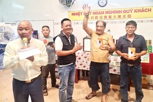 理事長鄭成龍（左）主持慶祝關平太子寶誕聚會上的幸運抽獎活動。