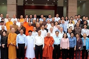 國家主席阮春福（前排左五）和市領導與諸位具威信華人同胞、 各宗教代表等合照留念。（資料圖）