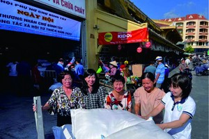 華人商販應氏蓮與平西市場商販派發食品給貧困者。