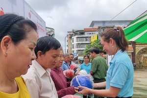该坊党委书记姜黎垂英向居民赠送安全帽。