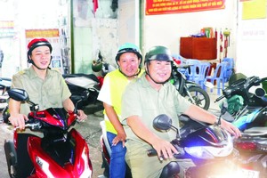 第四郡第十四坊人民巡逻组副组长梅明幸（中）与组员们一起在辖区巡逻。