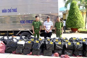 Đối tượng Thiện cùng tang vật hơn 20.000 bao thuốc lá lậu. Ảnh: TUẤN QUANG