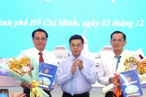Phó Chủ tịch UBND TPHCM Nguyễn Văn Dũng trao quyết định và hoa chúc mừng ông Trương Công Huy và ông Phan Tấn Thảo