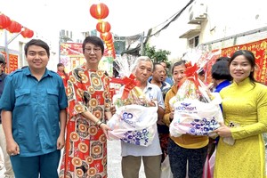 唐金萍女士（左二）与坊、街区代表向群众发送春节礼物。