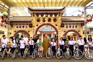 释慧功和尚和邓栢荣家眷向孤儿学生赠送自行车。