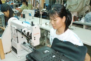 Workers make leather bags for export at a company in District 12 in Ho Chi Minh City. (Photo: SGGP)