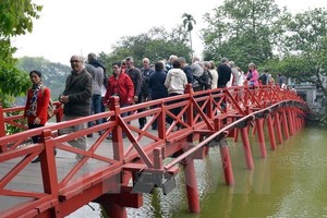 Tourists stand on "The Huc" Bridge, which leads to Ngoc Son Temple on Hoan Kiem Lake in Hanoi (Photo: VNA)