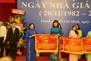 Head of the Department of Propaganda and Training of the HCMC Party Committee Than Thi Thu (in blue Ao Dai) presents the Government’s emulation flag to the City’s Department of Training and Education. (Photo: Sggp)