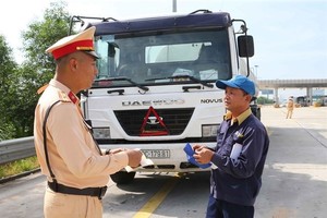 A member of the traffic police checks the paperwork of a truck driver on the Hanoi-Hai Phong Expressway. (Photo: VNA)