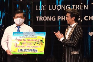 Pop star Dam Vinh Hung offers money to a representative of the Vietnam Fatherland Front's Ho Chi Minh City chapter.