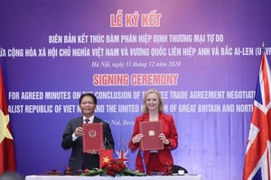 Minister of Industry and Trade Tran Tuan Anh and UK Secretary of State for International Trade Liz Truss sign the agreed minutes on the conclusion of negotiations over the UK-Vietnam Free Trade Agreement on December 11. (Photo: VNA)