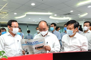 President Nguyen Xuan Phuc (C) and Secretary of the Party Committee of HCMC Nguyen Van Nen (L) visit the SGGP Newspaper. (Photo: SGGP)