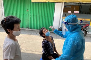 A health worker takes a sample from a woman for Covid-19 test at an area on Cao Thang Street in Phu Nhuan District. (Photo: SGGP)