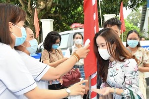 Healthcare workers measure voters' body temperature. (Photo: SGGP) 