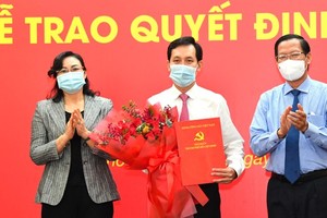 Standing Deputy Secretary of HCMC’s Party Committee Phan Van Mai (R) and Vice chairwoman of the municipal People's Committee, Phan Thi Thang (L) congratulate Mr. Vu Anh Khoa. (Photo: SGGP)