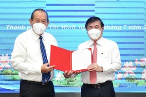 Deputy PM Truong Hoa Binh (L) hands over the appointment decision to Chairman of the HCMC People’s Committee Nguyen Thanh Phong (R). (Photo: SGGP)