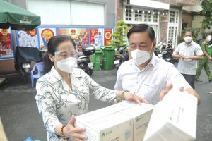 Chairwoman of the municipal People’s Council Nguyen Thi Le (L) and Secretary of the Party Committee of District 3 Pham Thanh Kien present gifts to the frontline force in Ward 12.