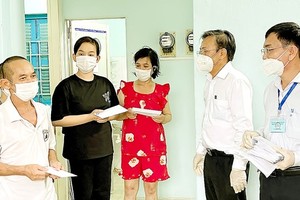Head of HCMC Commission of Mass Mobilization Nguyen Huu Hiep (2nd, R) offers gifts to households that move to temporary accommodation in Thanh Da Trade Union hotel in Binh Thanh District amid pandemic. (Photo: SGGP)