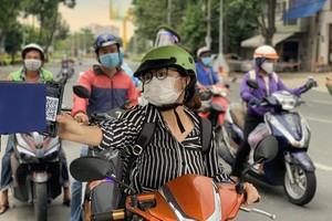 Residents provide health declaration QR Code at the checkpoint on Dinh Bo Linh Street in Binh Thanh District. (Photo: SGGP)