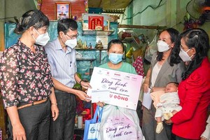 Deputy editor-in-chief of the SGGP Newspaper Pham Van Truong (2nd, L) presents a gift to a needy pregnant woman. (Photo: SGGP) ​