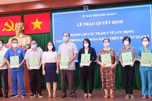 Vice chairwoman of the People’s Committee of District 7 Nguyen Thi Be Ngoan hands over the decision on establishing mobile healthcare stations. (Photo: SGGP)