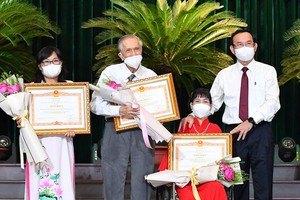 Secretary of the HCMC Party Committee Nguyen Van Nen (R) congratulates outstanding individuals at the award ceremony.