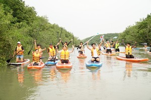 Visitors participate in a stand up paddle (SUP) tour crossing a mangrove forest in Can Gio District.