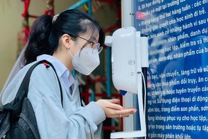 Students of the Luong The Vinh High School in District 1 take measurement of body temperature  and wash their hands before entering the class.