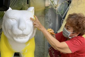 A worker is painting a replica of a tiger.