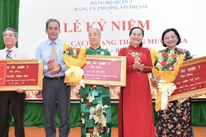 Chairwoman of the HCMC People’s Council Nguyen Thi Le (2nd, R) presents Party membership badges to Party members of District 3.