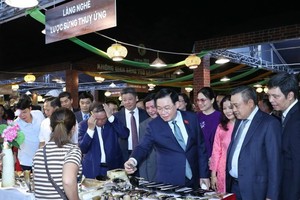 NA Chairman Vuong Dinh Hue visits a display booth at the festival. (Photo: SGGP)