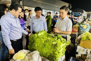 Vice Chairman of the HCMC People's Committee Nguyen Van Dung (R) conducts an inspection of the Hoc Mon Agriculture Wholesale Market. (Photo:SGGP)