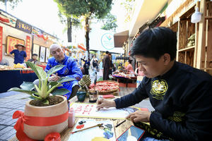 Calligraphers wear traditional costumes and write and sell nice words written in calligraphy to customers wishing for health, prosperity, and good luck throughout the new year. (Photo: SGGP)