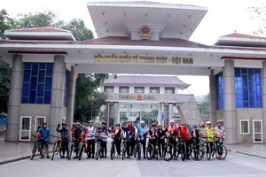Participants in the bicycle tour pose for a photo at the Thanh Thuy International Border Gate in Ha Giang province. (Photo: baohagiang.vn)