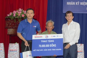Journalist Nguyen Khac Van, Deputy Editor-in-Chief in charge of Sai Gon Giai Phong Newspaper (R) and a representative of the sponsors provide funding to build and repair houses for wounded veteran Pham Van Thien. (Photo: SGGP)