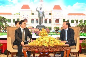 Director of the Institute of Party History and Literature of the CCP Central Committee Qu Qingshan (L) informs the results of the third plenary session of the 20th Central Committee of the Communist Party of China to Chairman of the HCMC People’s Committee Phan Van Mai. (Photo: SGGP)