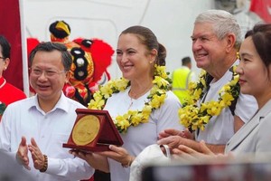Chairman of the provincial People's Committee Cao Tuong Huy (L) offers flowers to Ms. Tina Bogle and her husband. (Photo: SGGP)