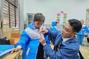 Journalist Nguyen Hung presents a sweater to a student of the Doc Gop School. (Photo: SGGP)