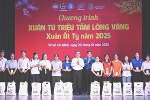 Vice Secretary of the Ho Chi Minh City Party Committee Nguyen Phuoc Loc (8th, L) and Secretary of the HCMC Youth Union cum President of Vietnam Youth Federation (VYF) in HCMC Ngo Minh Hai (7th, R) offer Tet gifts to disadvantaged students. (Photo: SGGP)