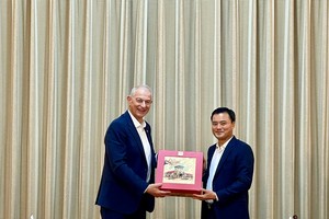 Vice Chairman of the Ho Chi Minh City People's Committee Bui Xuan (R) offers a gift to Mr. Reha Denemec. (Photo: SGGP)