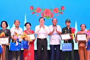 Former State President Truong Tan Sang (4th, L) and former Deputy Prime Minister Truong Hoa Binh (3rd, R) offer gifts to former political prisoners and prisoners of war.