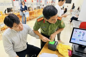 A police officer instructs a foreigner how to register for a level-2 electronic identification account. (Photo: VNA)