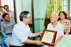 Mr. Nguyen Phuoc Loc (L) presents a congratulatory card marking her 100th birthday, along with a gift from State President Luong Cuong, to Ms. Ho Thi Quoi. (Photo: SGGP)