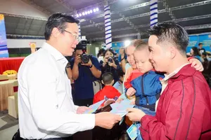 Le Quoc Phong, Permanent Deputy Secretary of the Ho Chi City Party Committee, presents gifts to workers before they get on buses to return to their hometowns. (Photo: SGGP)