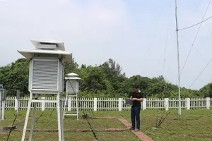 Meteorological observation officers collect weather data at a monitoring station.